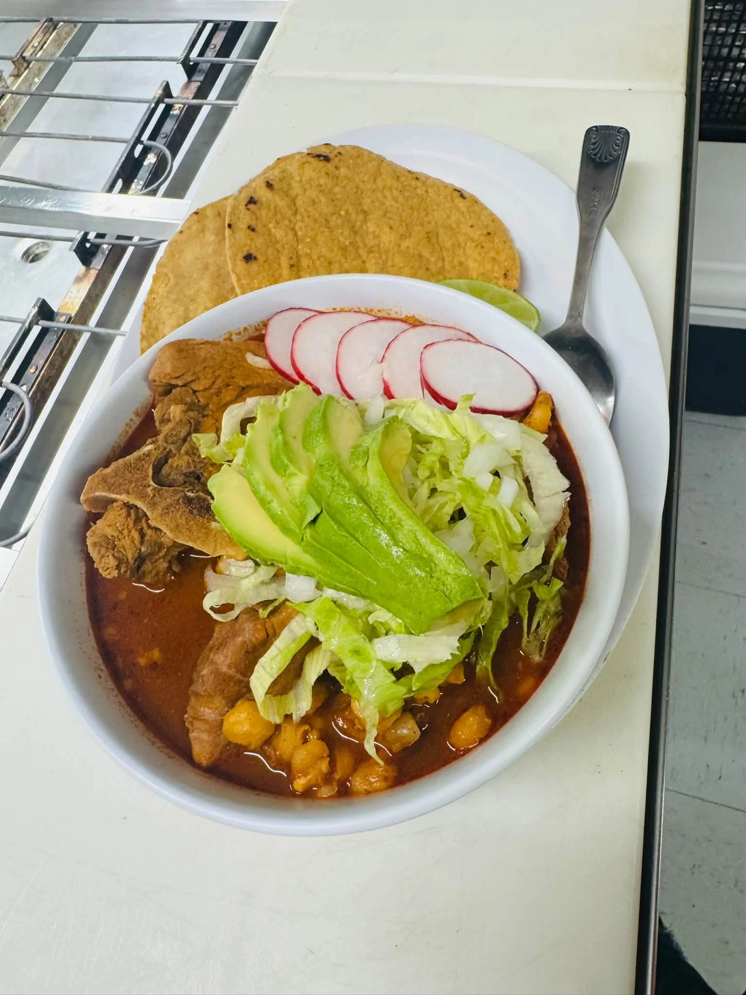 A fresh house soup served with avocado, radish, lime and tortillas at Carniceria Camargo